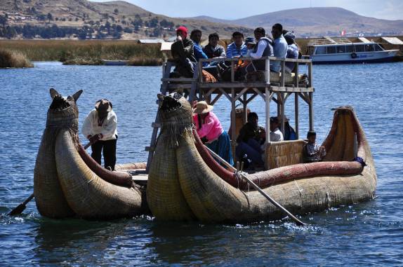 Os Uros levam turistas para passear em barco típico, nas Islas flotantes do lago Titicaca, perto de Puno, no Peru